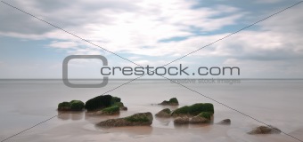Beach rocks long exposure with cloudy sky