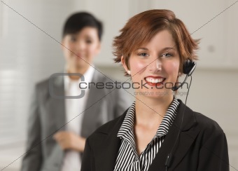 Pretty Red Haired Businesswoman and Colleague with Headset in Office Setting.