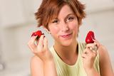 Pretty Red Haired Woman Eating Strawberry in Her Kitchen.