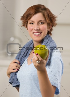 Pretty Red Haired Woman with Towel Holding Green Apple in Her Kitchen.