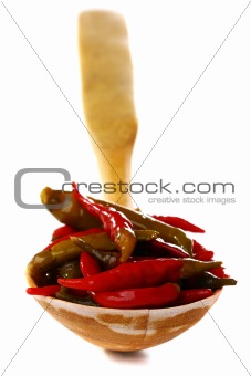 Pickled hot chili peppers in a wooden spoon.
