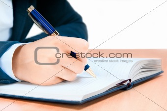 Cropped image of hand of young woman taking notes