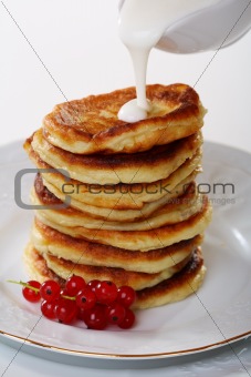 Pancakes with sour cream sauce and red currants. 