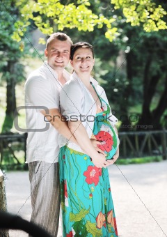 Happy pregnant couple at beautiful sunny day in park