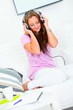 Lovely woman relaxing on sofa and listening music in headphones
