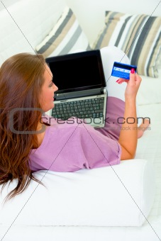 Woman sitting on sofa with laptop and credit card
