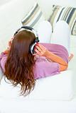 Woman sitting on sofa and listening music in headphones
