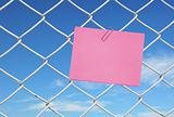 yellow note on chain link fence see blue sky
