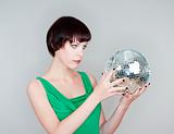 young woman holding a disco ball looking - isolated on gray