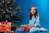 Girl and christmas presents near christmass tree
