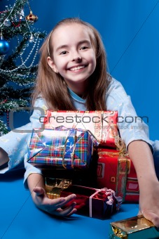 Girl and christmas presents near christmass tree