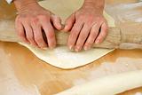 Hands on rolling pin over dough