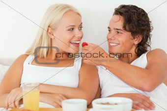 Cute man giving a strawberry to his girlfriend