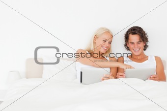 Laughing couple using tablet computers
