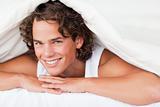 Man under a duvet with a knowing smile