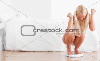 Cheerful woman squatting on a weighing machine