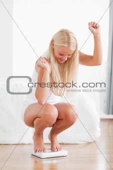 Portrait of a sportive woman squatting on a weighing machine
