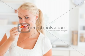 Blonde woman eating a slice of pepper