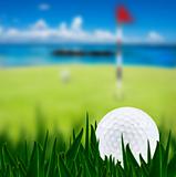 Golf ball on a golf course with a green and the beach in the background