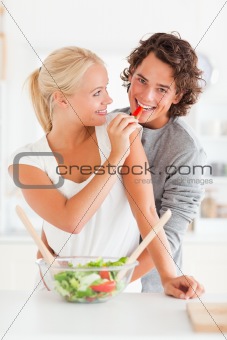 Portrait of a woman giving a slice of pepper to her fiance