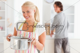 Portrait of a woman posing while a man is washing the dishes