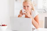 Woman having a tea while using her laptop