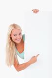 Blond-haired smiling woman pointing at a whiteboard