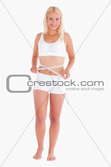Young blond lady measuring her waist