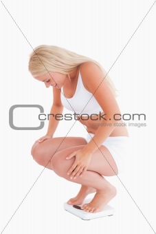 Young woman crouching on a scale