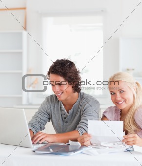 Happy couple with bills and laptop