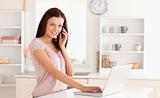 Woman telephoning with hand on laptop