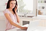 Woman telephoning while working at laptop