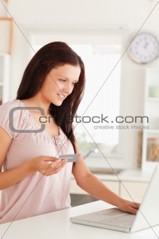 Woman holding credit card and looking at laptop
