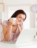 Woman holding cup of coffe at laptop