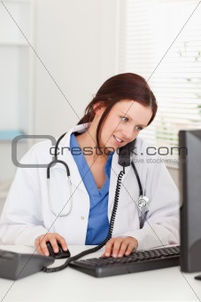Female doctor working in office and telephoning