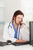 Female doctor telephoning by pc