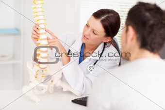 Female doctor pointing on bone in spine