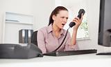 Depressed businesswoman shouting at telephone