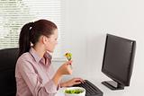 Businesswoman eating salad whilst looking to screen