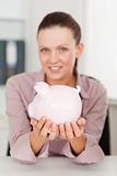 Businesswoman holding piggy bank in office