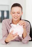 Businesswoman inserting money into piggy bank