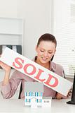 Businesswoman holding sold sing above model house