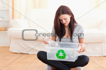 Cute woman putting bottles in a recycling box