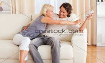 Happy couple fighting for the remote