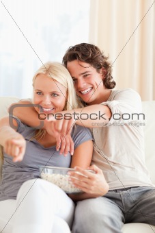 Portrait of a couple watching TV while eating popcorn