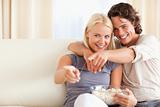 Cute couple watching TV while eating popcorn