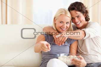 Cute couple watching TV while eating popcorn