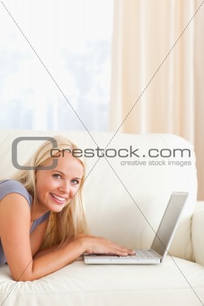 Woman lying on a couch with a laptop