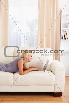 Portrait of a woman lying on a couch using a notebook