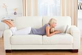 Woman lying on a sofa using a laptop